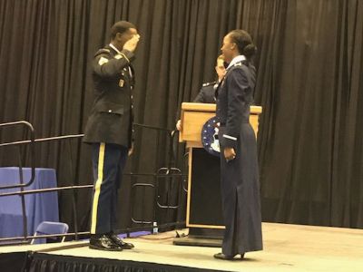 Ariana Mosley and Sgt Adrian Mosley are standing in front of one another saluting.